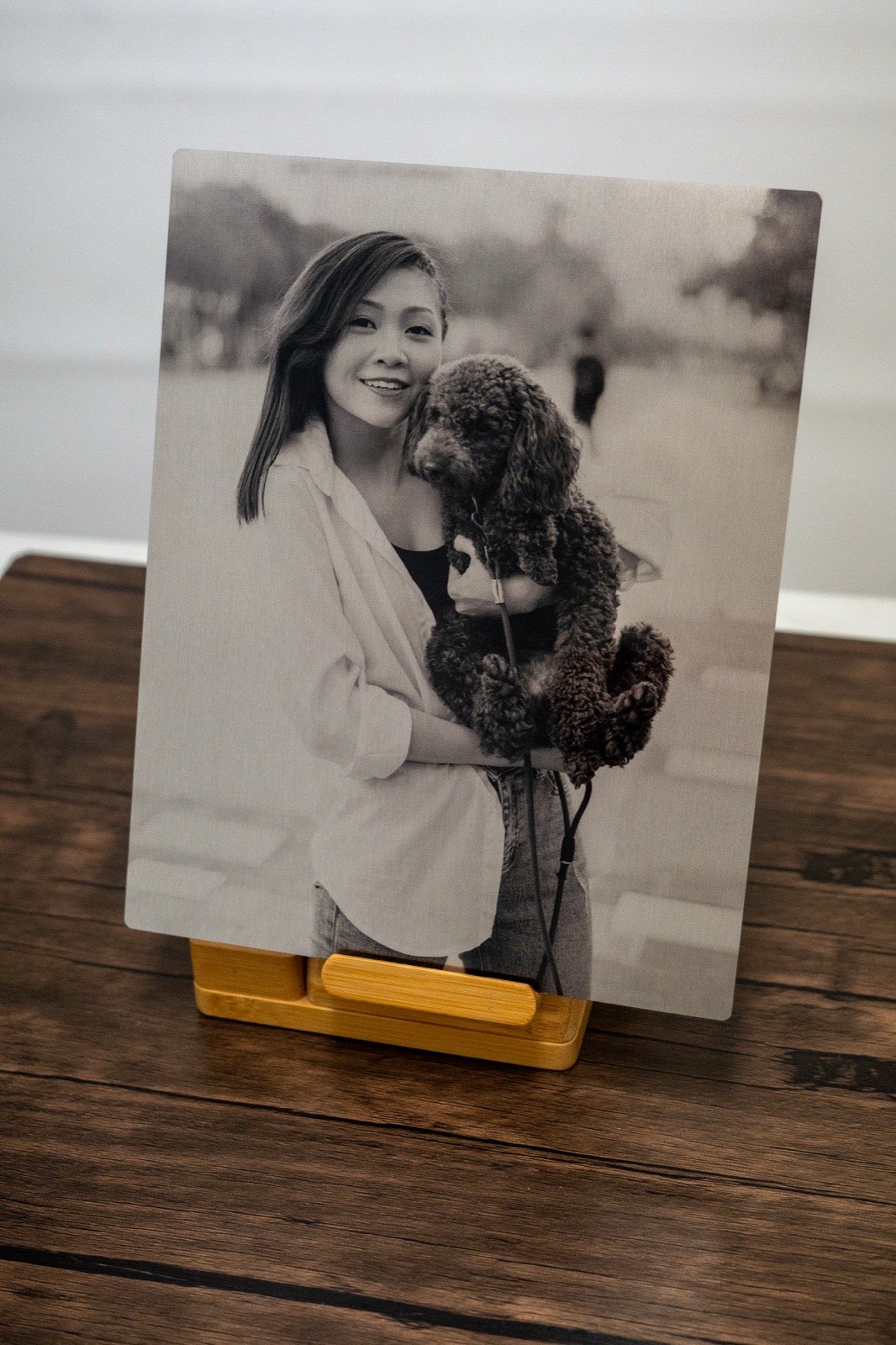 Black and white ChromaLuxe portrait of a woman holding a standard poodle, printed on coated aluminium.