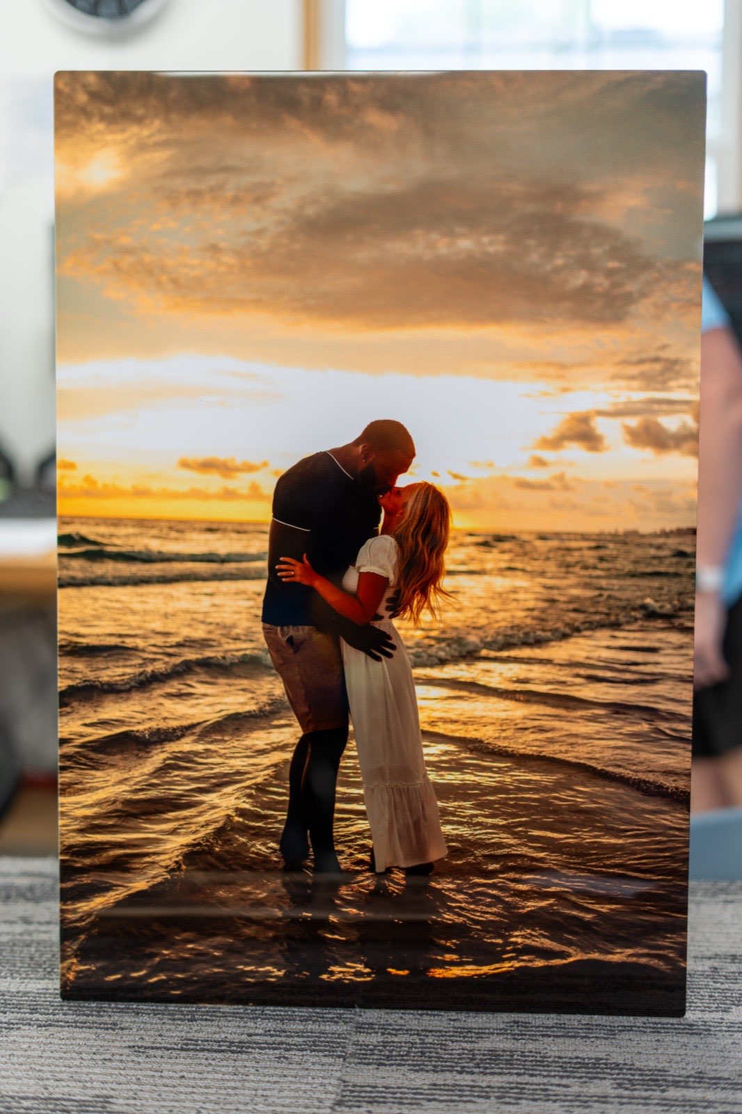 ChromaLuxe metal print of a couple embracing at the shoreline during sunset, printed edge-to-edge on coated aluminium.